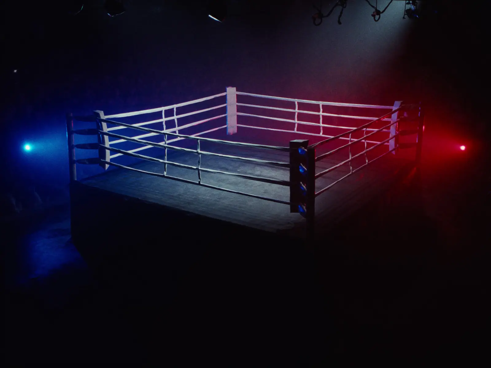 Empty boxing ring under spotlights with red and blue corner lights