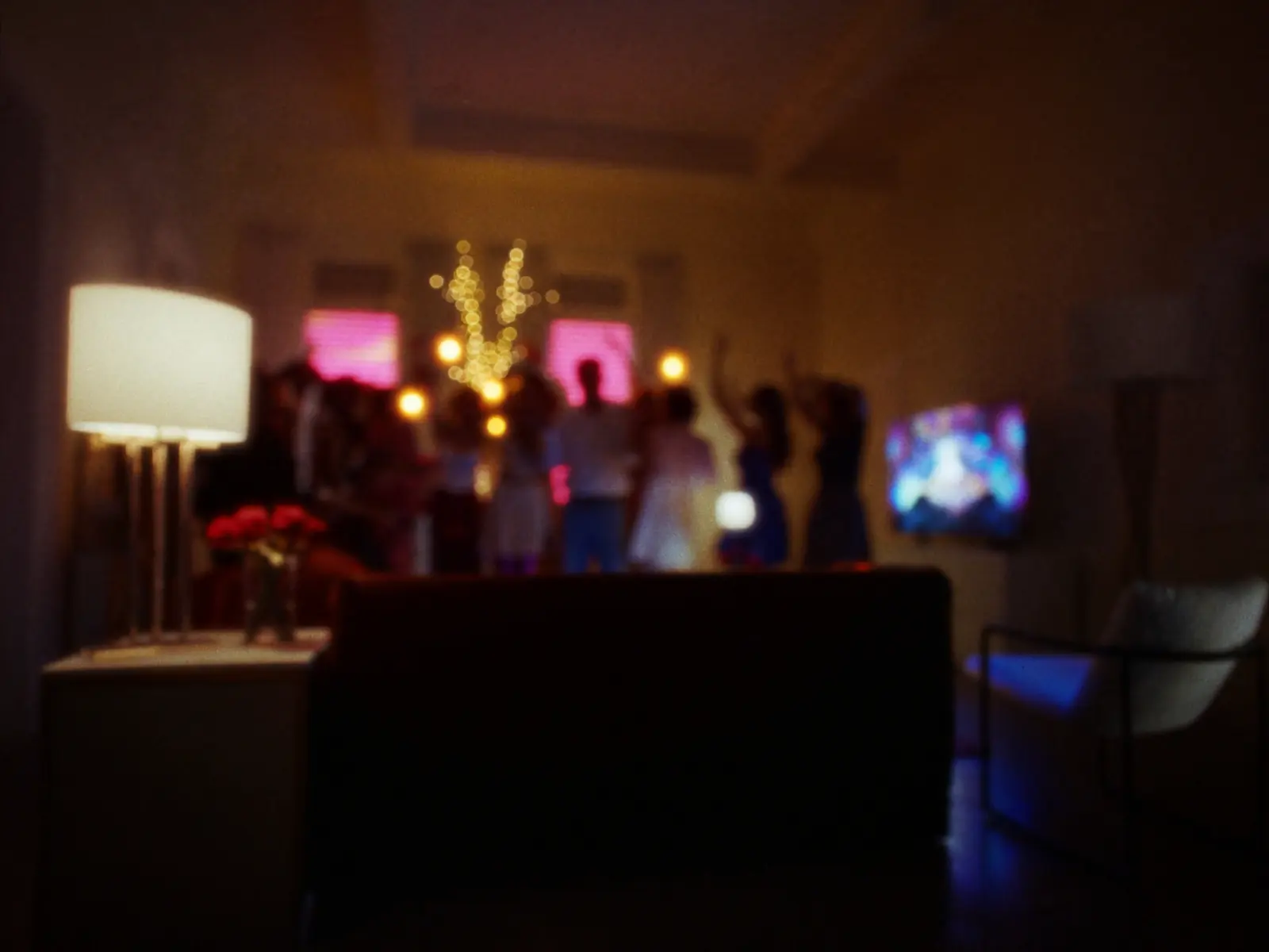 Friends celebrating in a warmly lit apartment with colourful bokeh lights